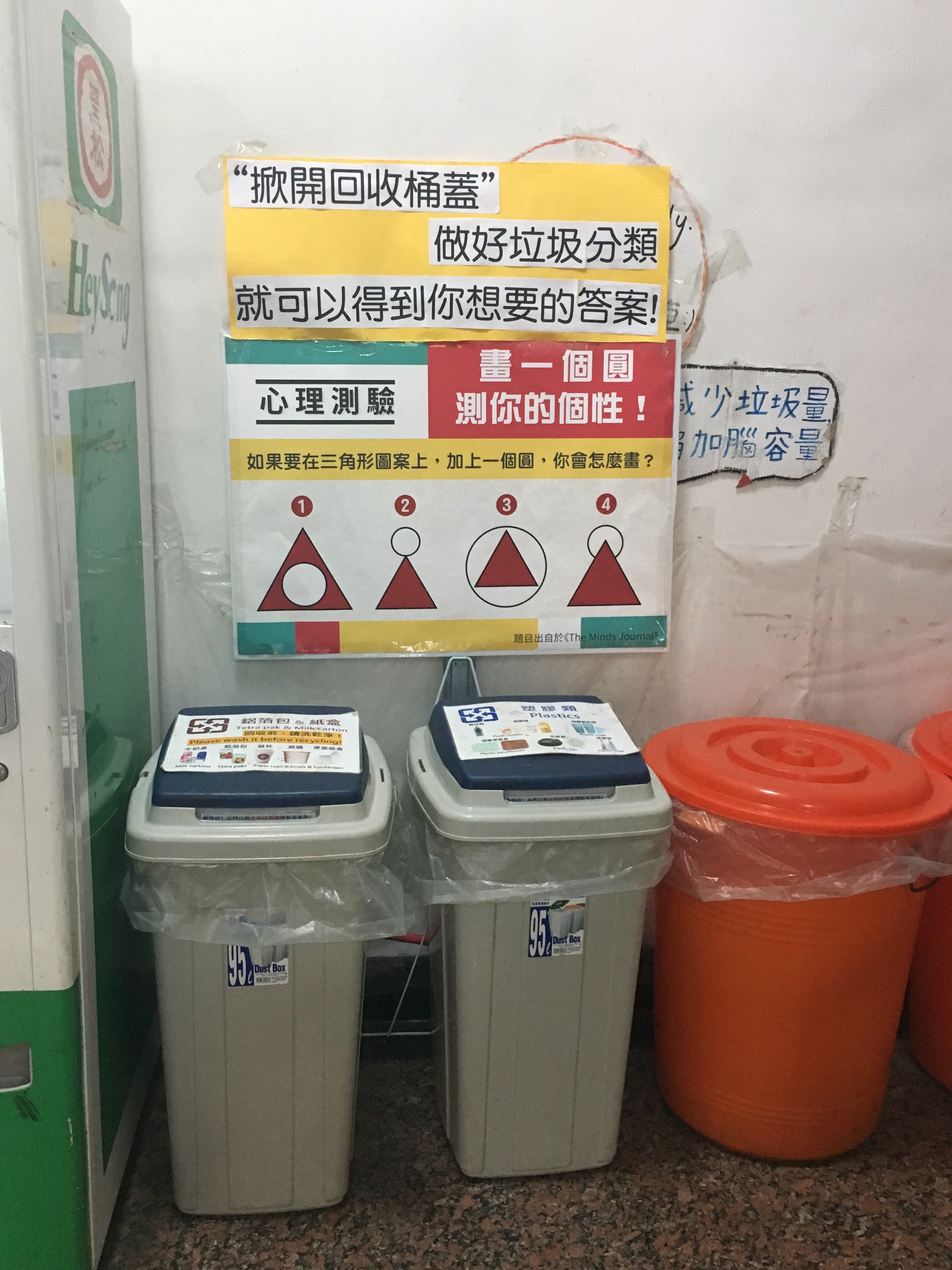 There is a poster above three recycling bins.