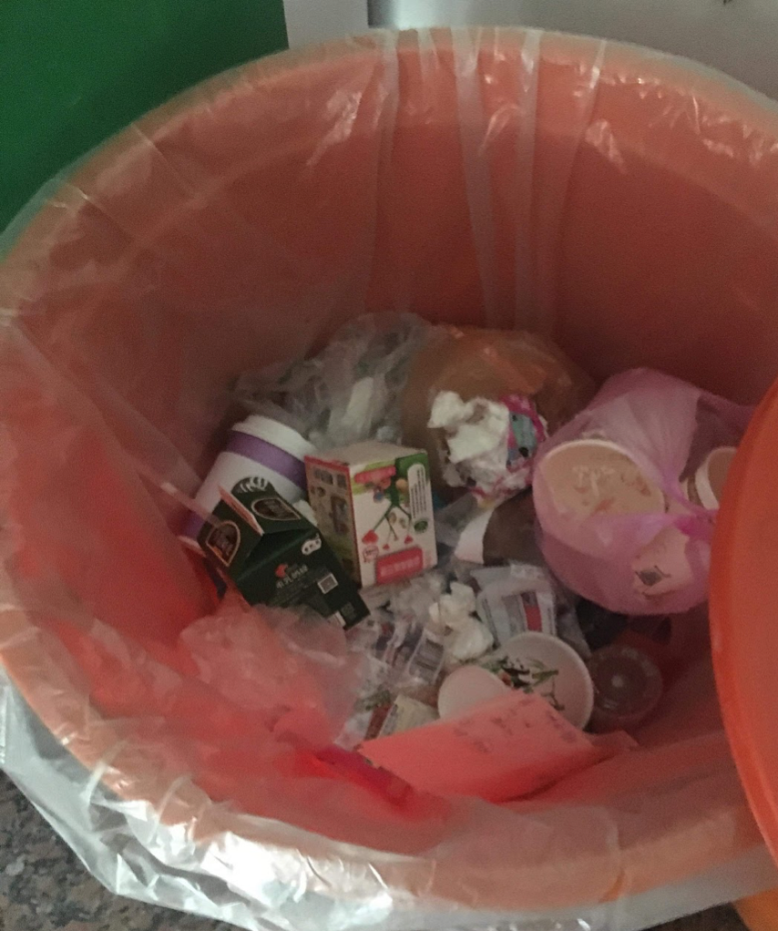 A trash bin full of messy trash and recyclable material.