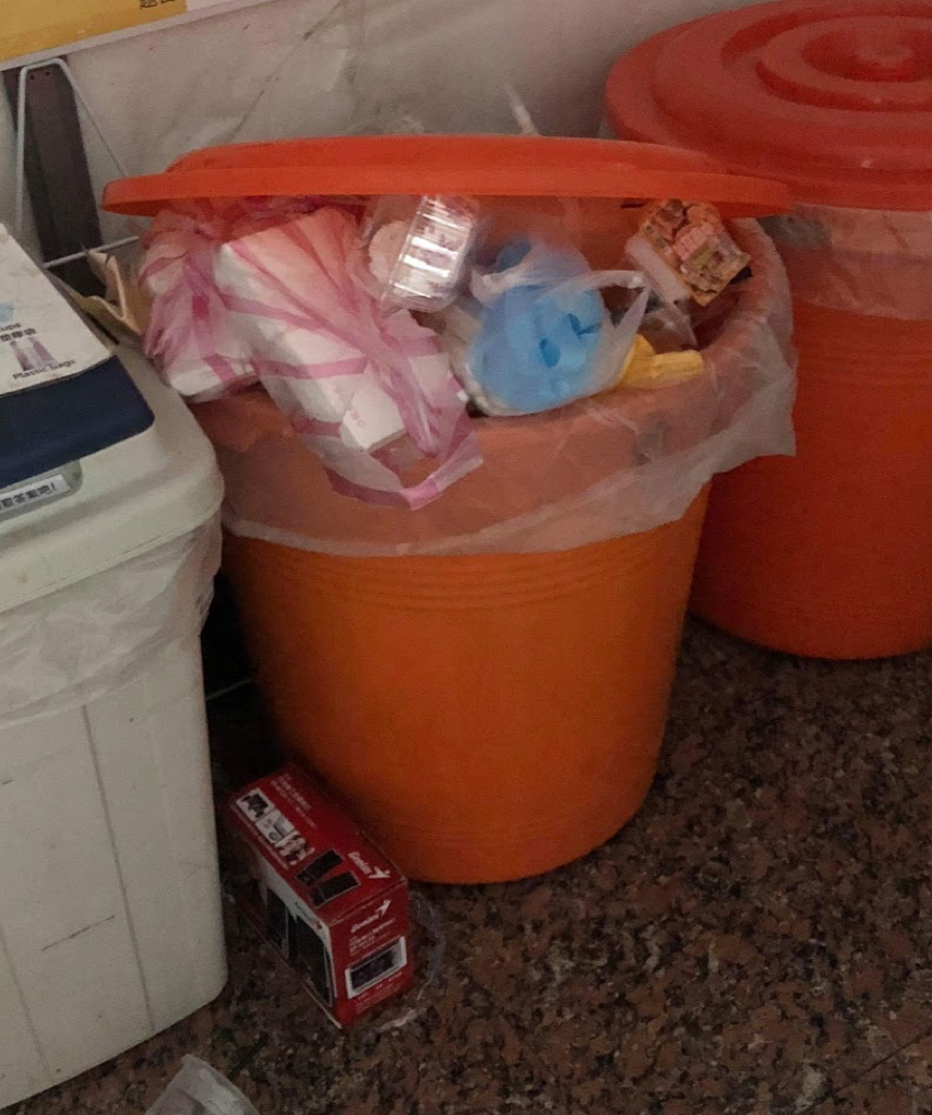 A trash bin full of messy trash and recyclable material.